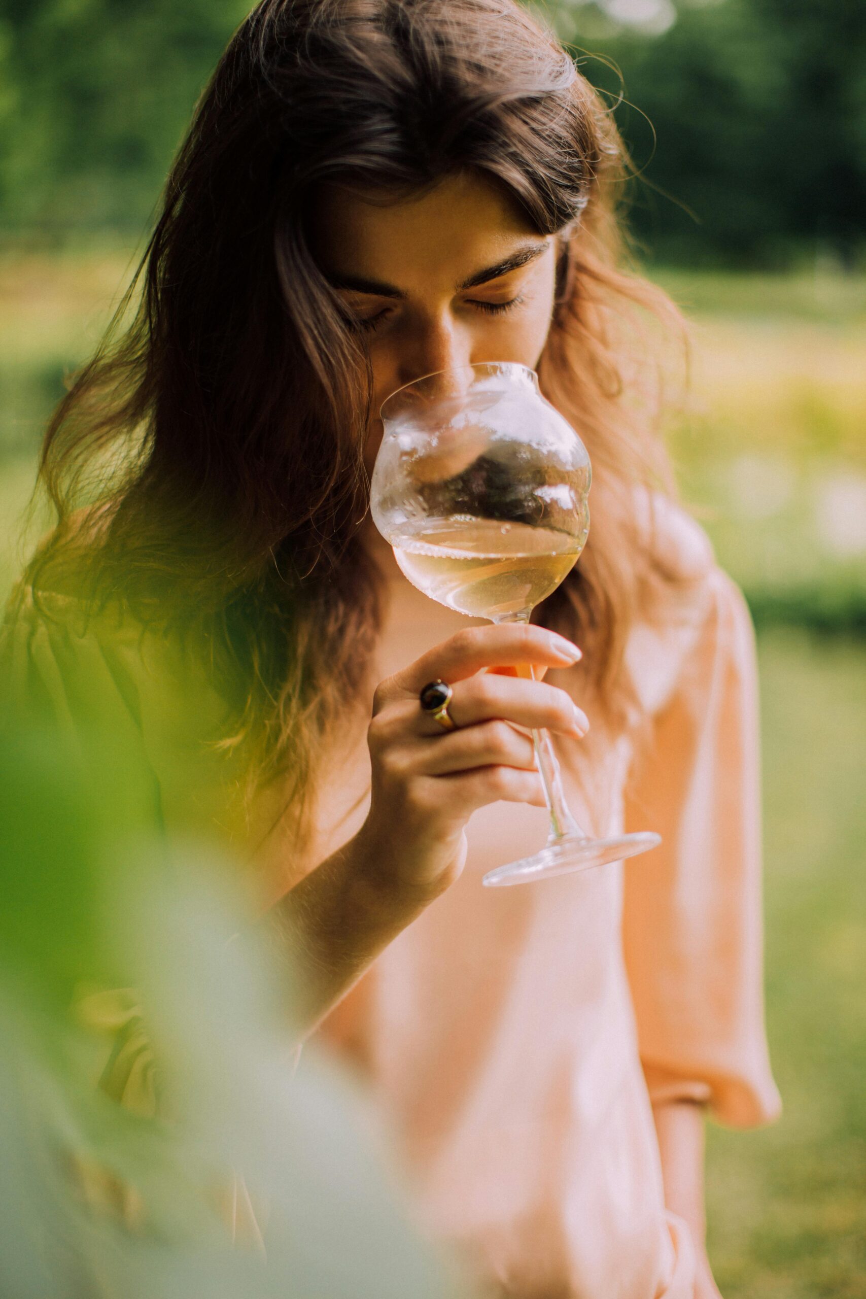 Túráink Woman enjoying a peaceful moment with a glass of white wine outdoors.